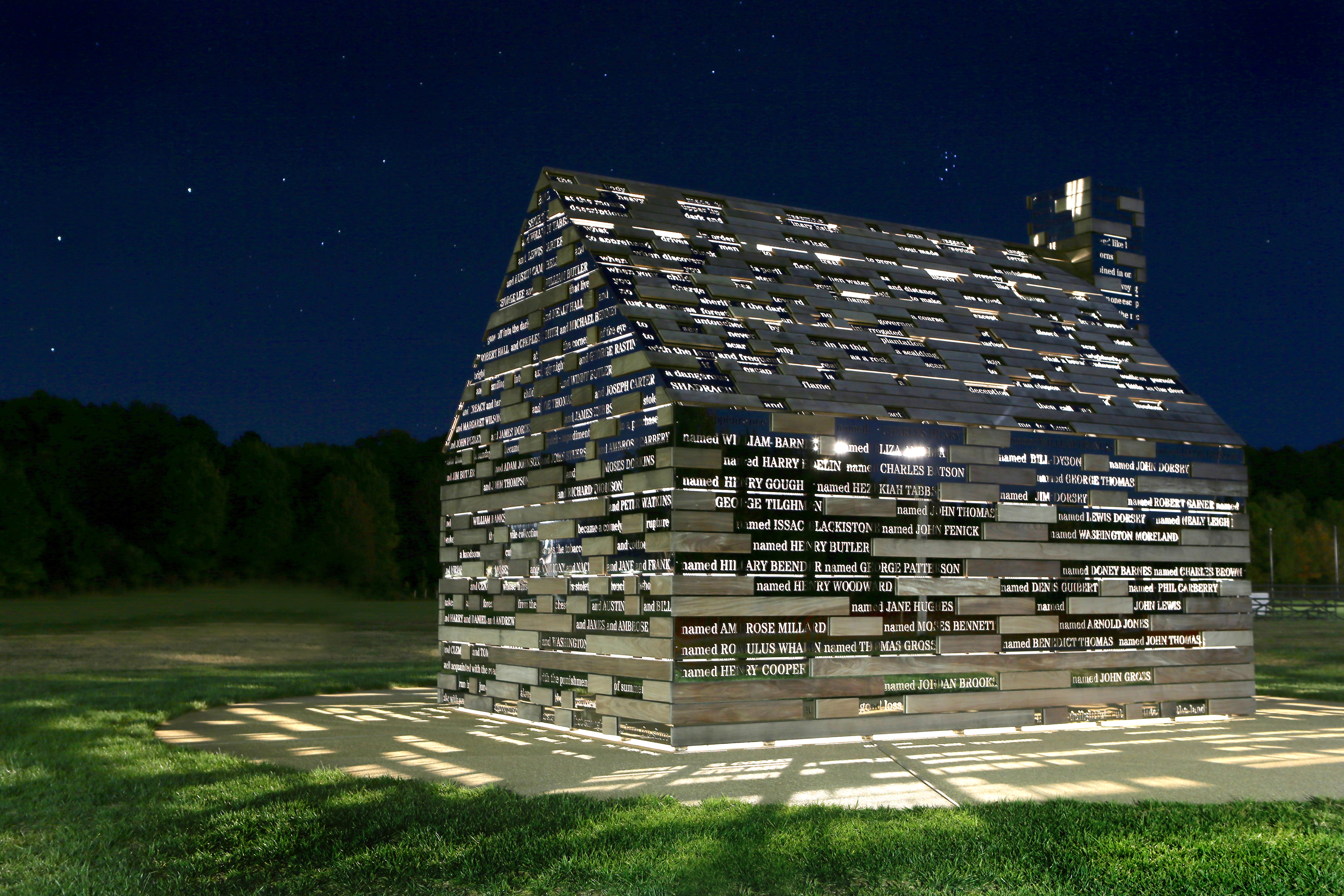 Cabin with reflective panels featuring names of former enslaved people who self liberated, taken at night.