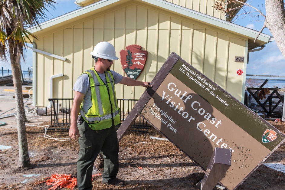 NPS crewmember props up an all-but-destroyed park sign