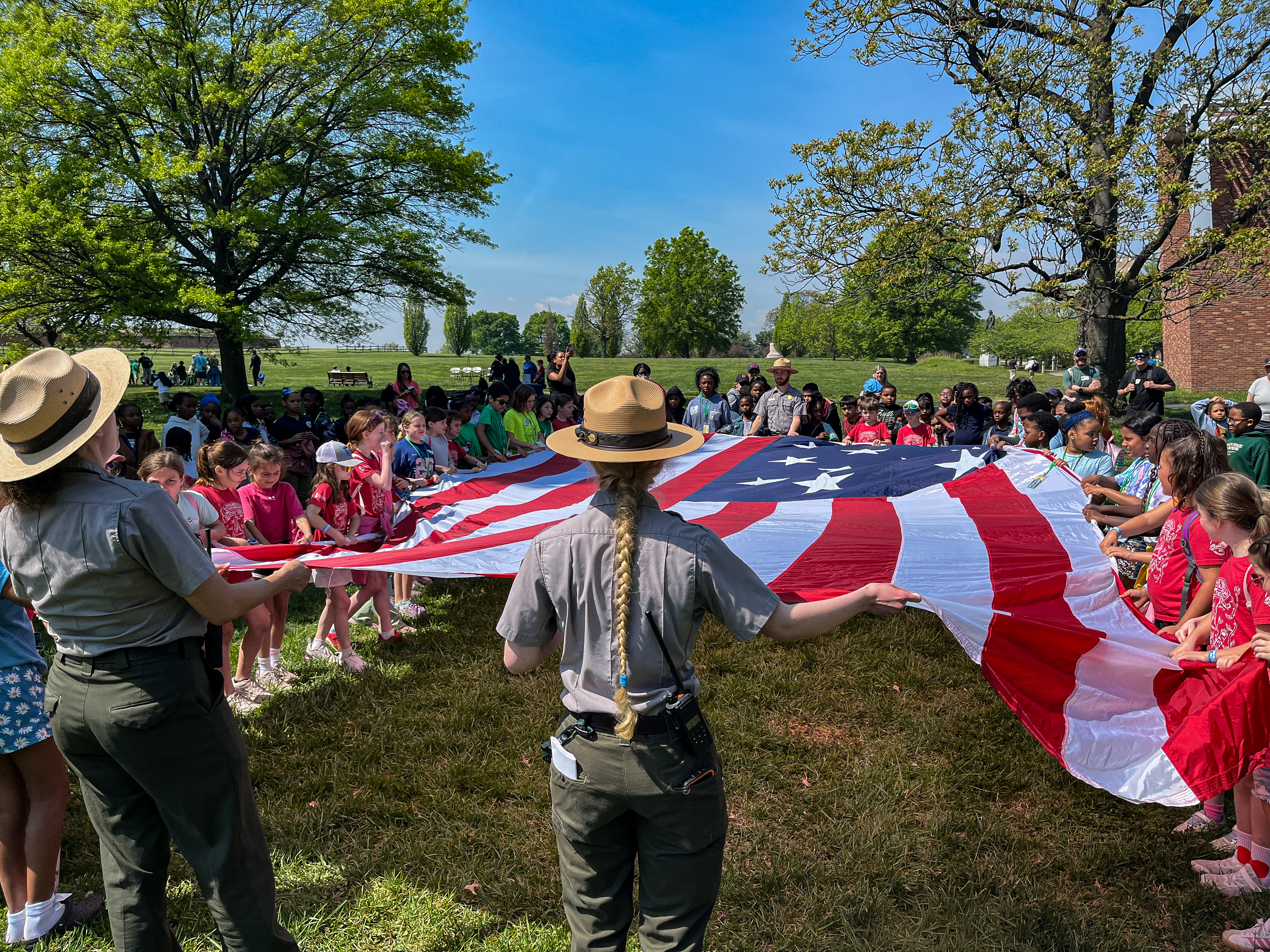 People holding an American flag on all sides and spreading it between them