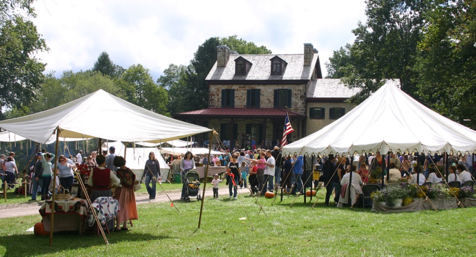 Crowd gathered under white tents in front of the Gallatin House