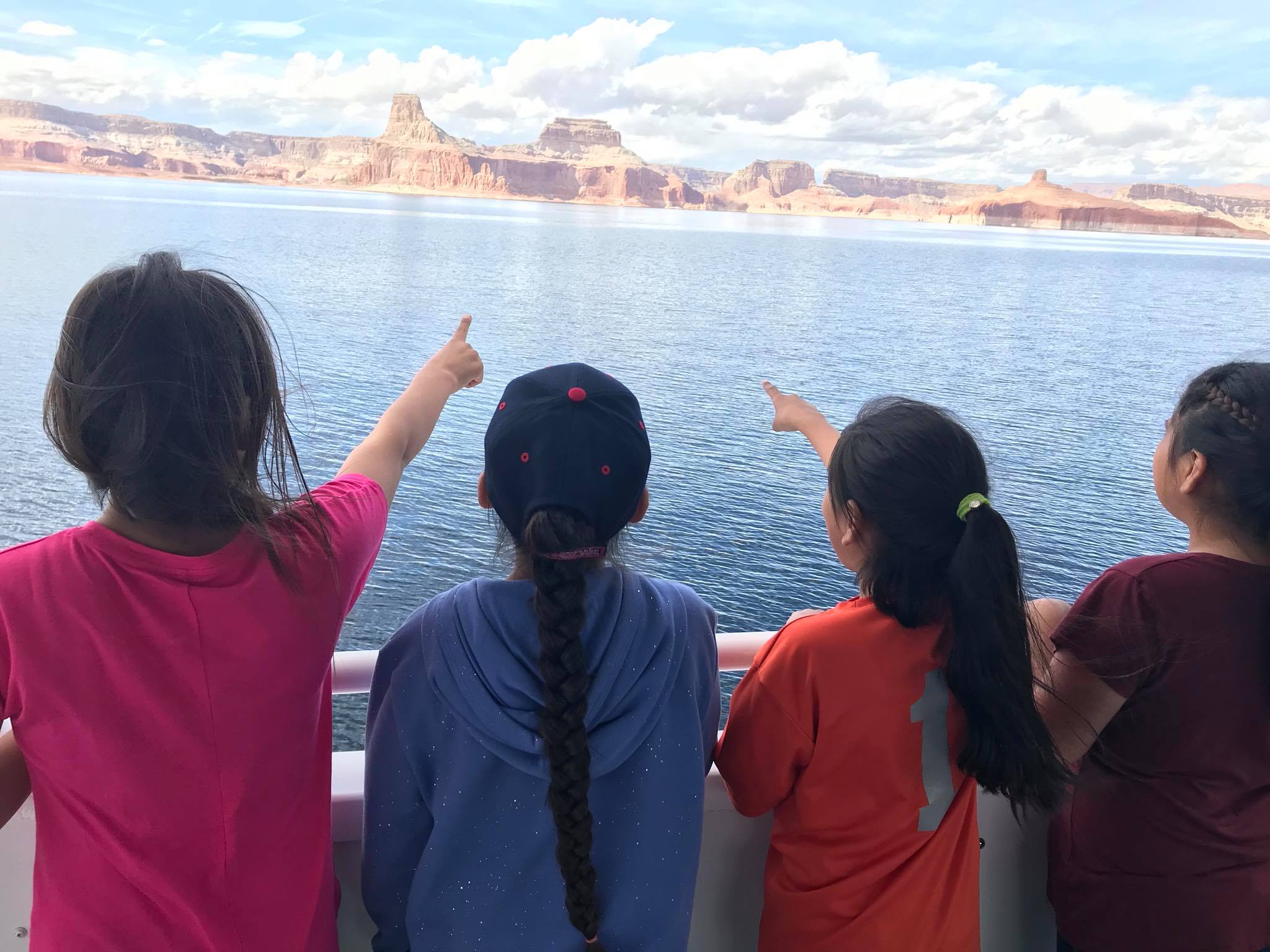 GLCA kids on boat four kids on a boat pointing across the water to a canyon wall