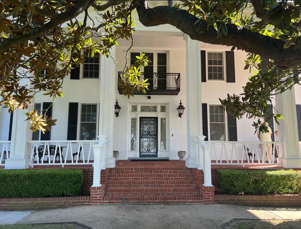 The historic Mansion House on the campus of Hampton University A white mansion with brick steps leading up to it.