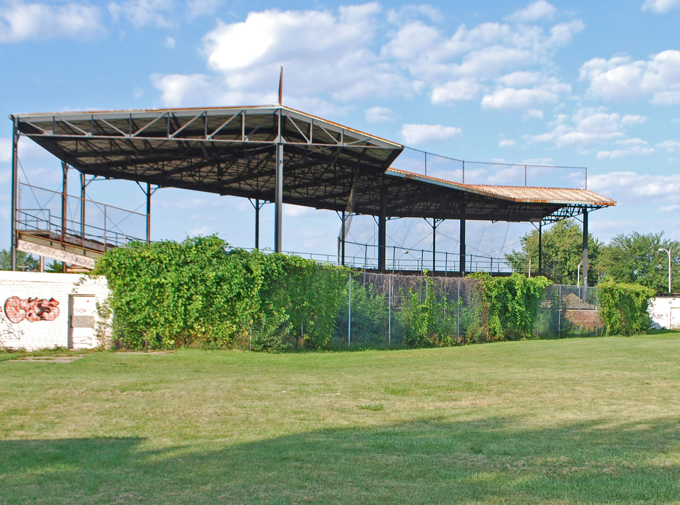 A metal stadium, a grass lawn in the foreground.