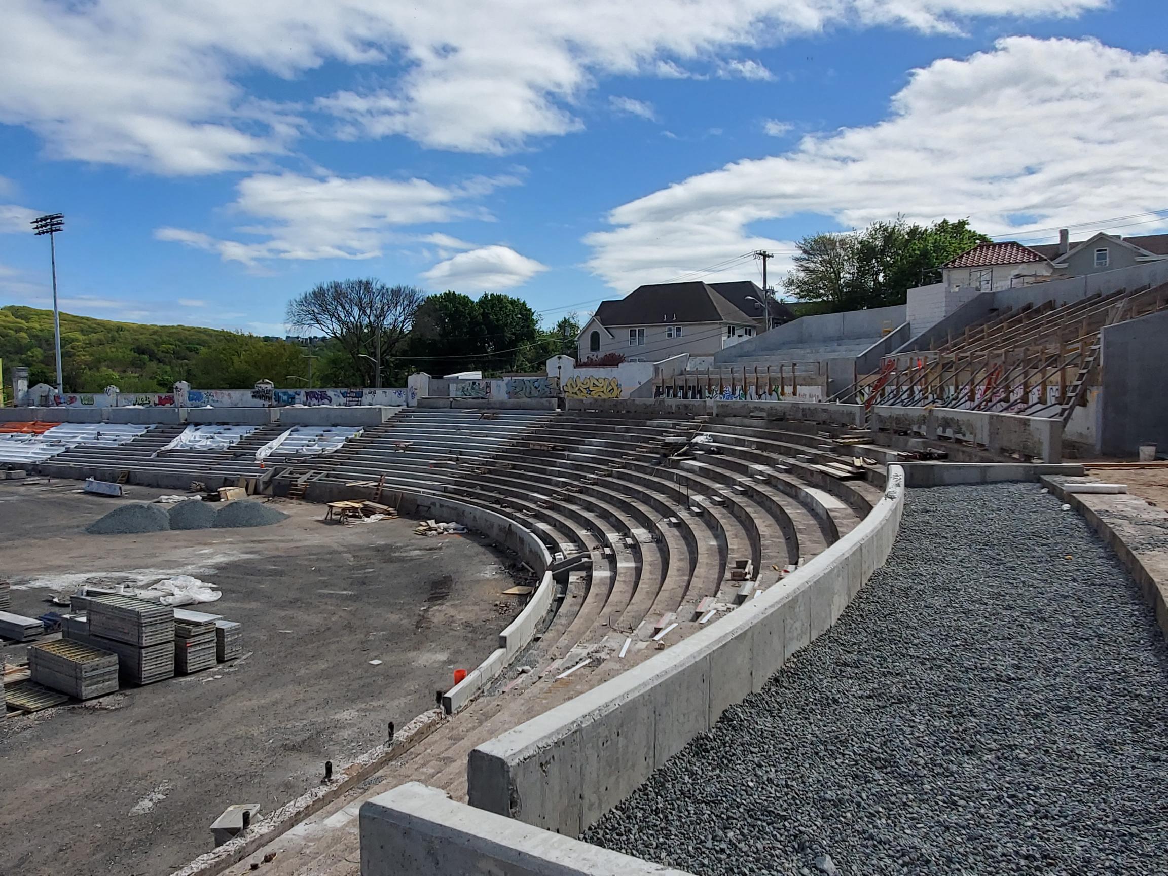 A vacant stadium with curved cement bleachers extending out and to the left.