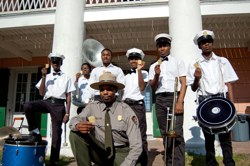 Park ranger and youth brass band holding up junior ranger badges