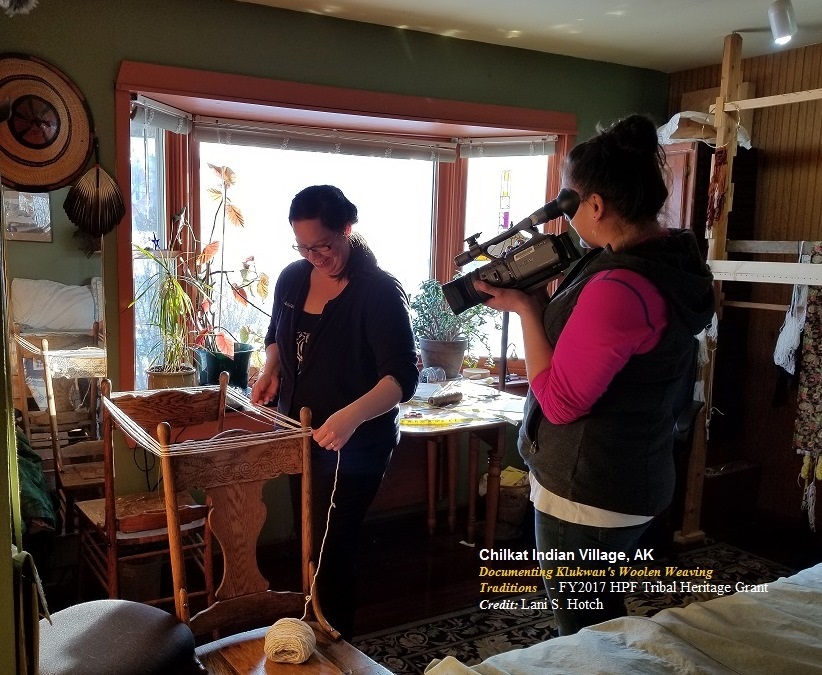 Woman filming another woman weave wool