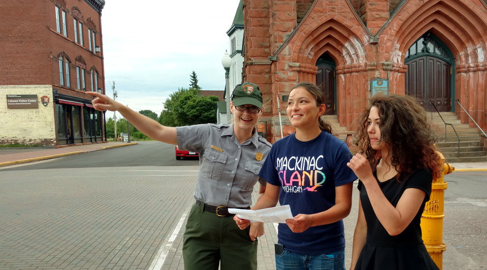 Park ranger pointing out historic buildings to two women