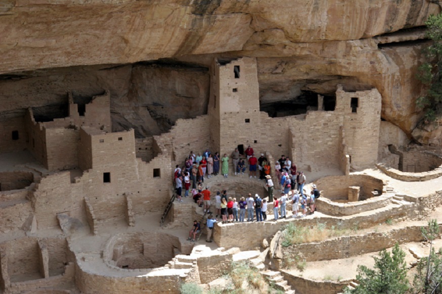 A crowd of visitors by ancient Pueblo ruins