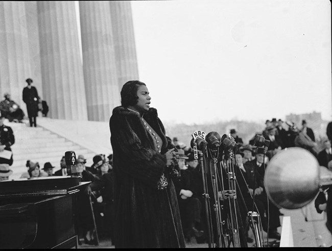 Historical black and white photo of Marian Anderson singing to a crowd on memorial steps