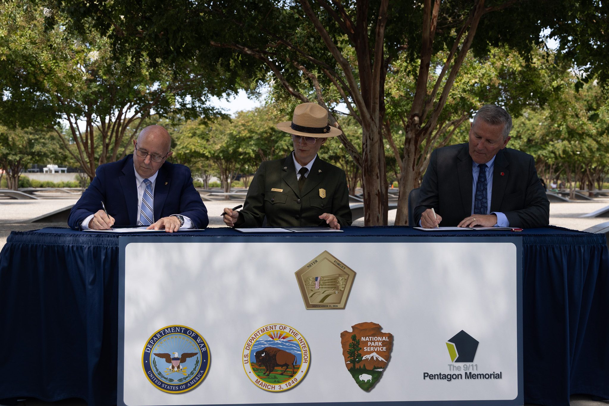 Three people at a table signing a document