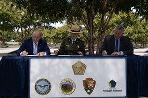 Three people at a table signing a document