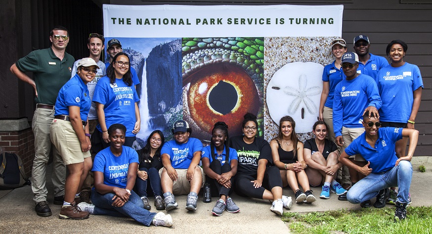 NCR SCAs Group of youth standing or sitting by a Centennial banner