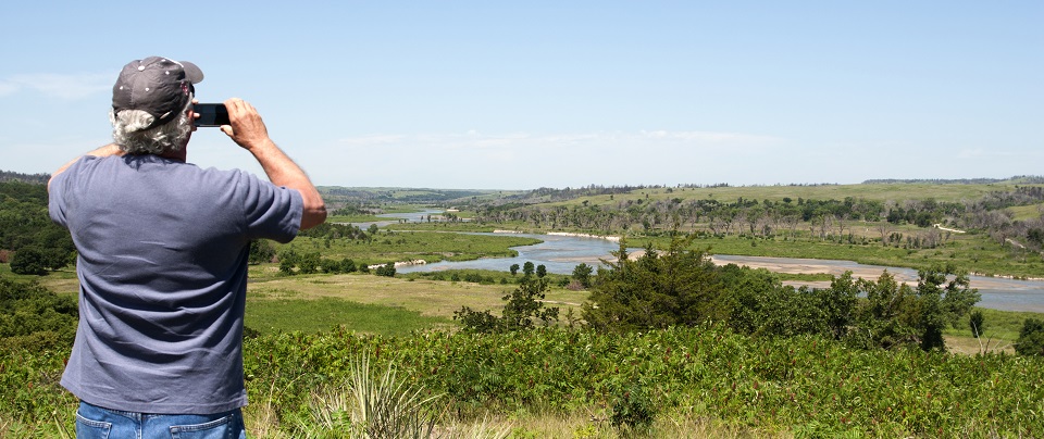 Man viewing a river valley through binoculars