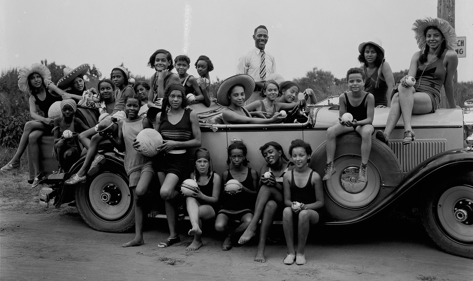 YMCA Camp Clarissa Scott, 1931 Twenty-two individuals pose for a photo sitting on or standing around a vehicle. The image is in black and white and was taken in 1931 at a YMCA camp.
