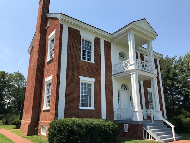 Photo of Vann House in Georgia Two story brick house in the middle of a large, grass field.