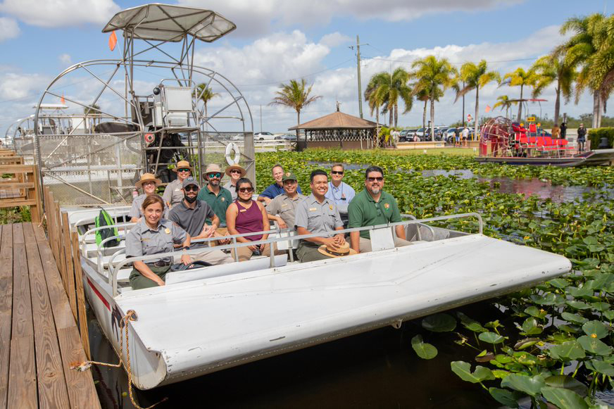 Director Sams joins park staff for an air boat ride in Everglades National Park. NPS staff sit together on a docked air boat in Florida's Everglades.