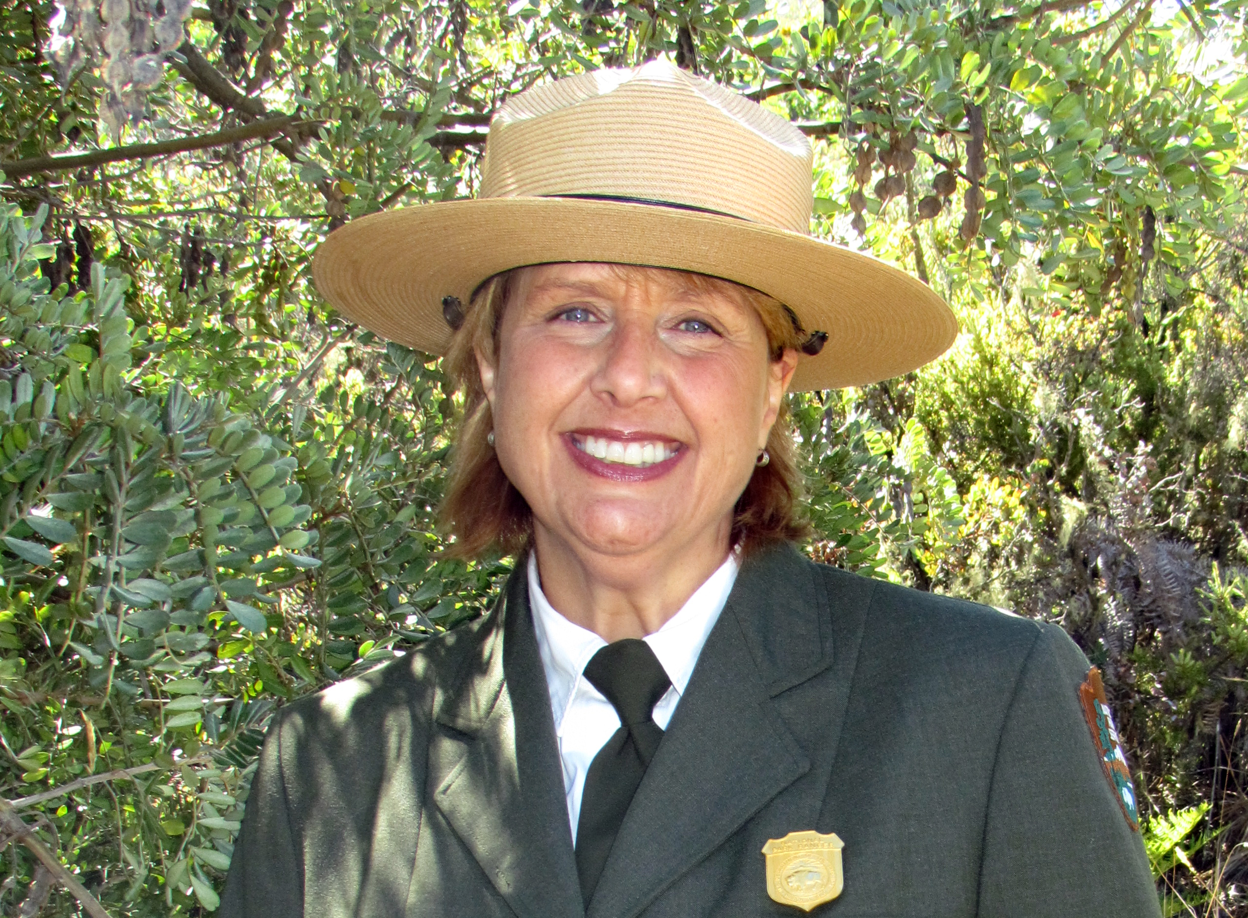Sarah-C_0994c A woman in an NPS uniform with a coat smiles for the camera outdoors.