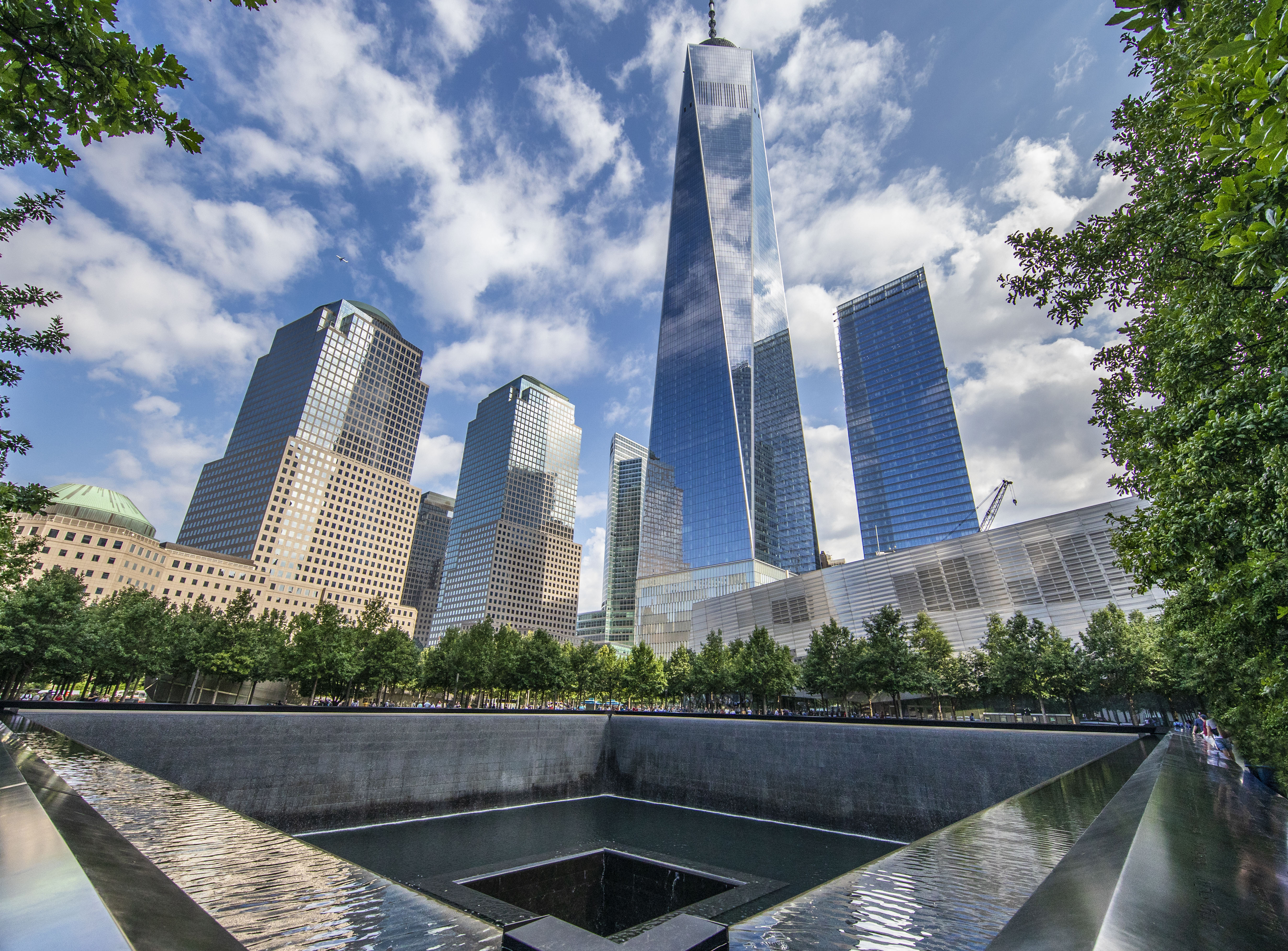 A square reflecting pool; in the background, several skyscrapers reach toward the sky.