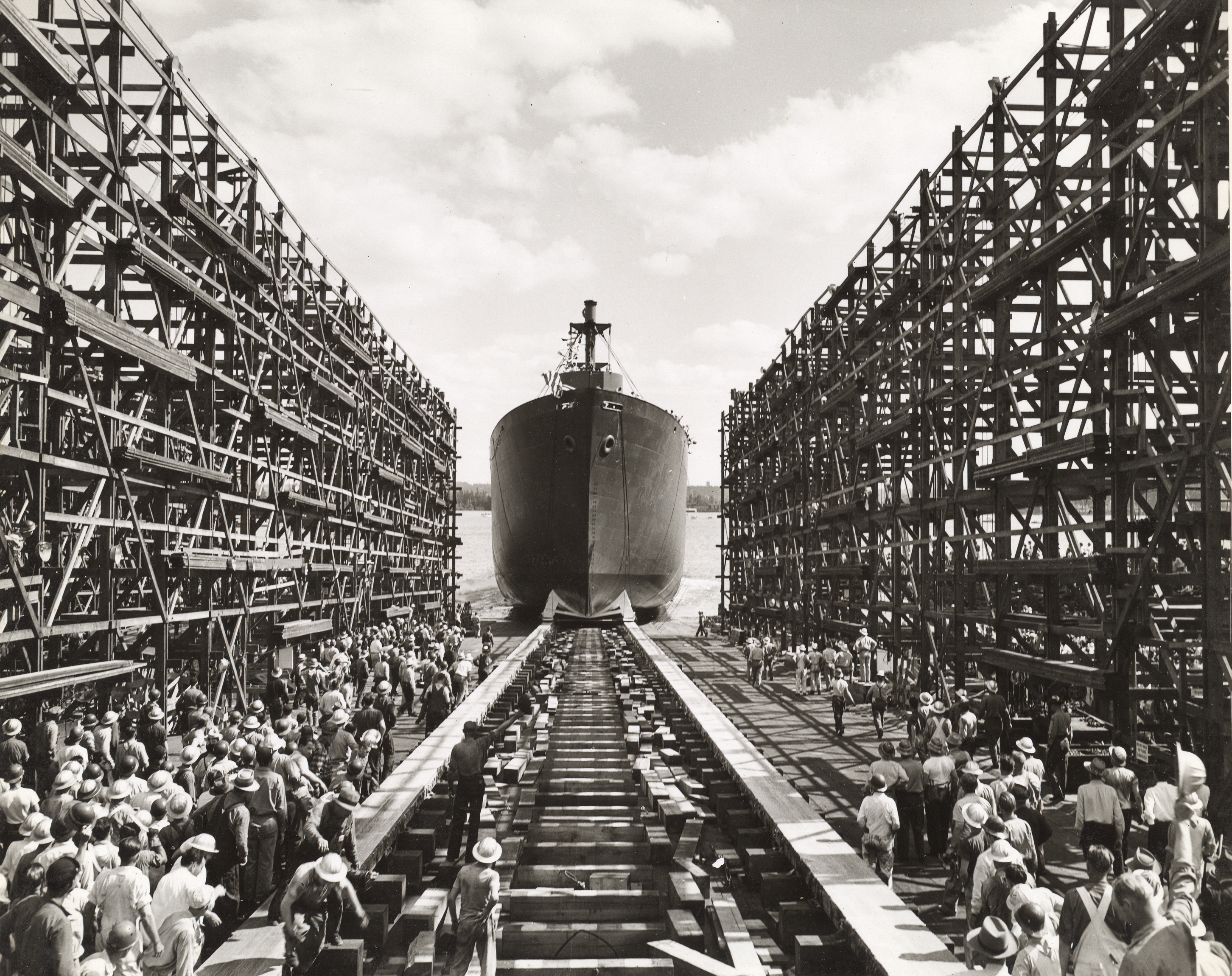 Ship launched at Kaiser Shipyards Ship launching from dry dock as workers look on