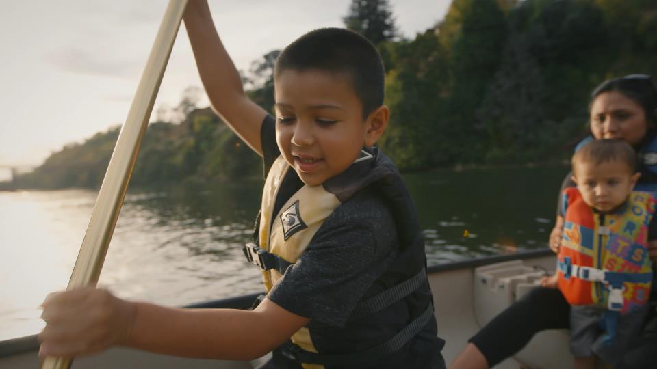 America's Wild and Scenic Rivers offer wonderful family-friendly activities. A young boy paddles a canoe along a river with his mother and young sibling