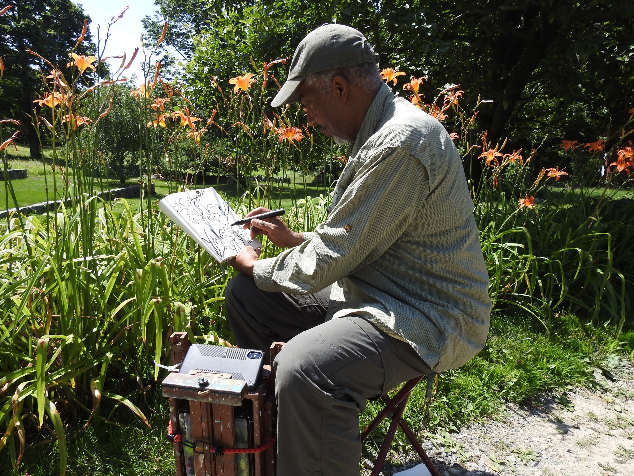 Man sitting in a field of flowers sketching what he sees