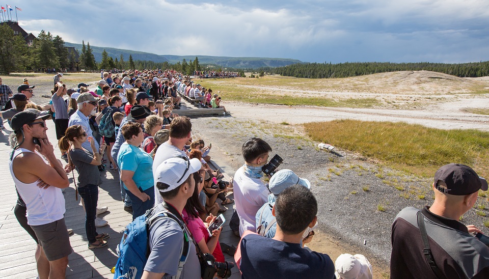 Group of visitors standing on a boardwalk waiting for geysers to erupt