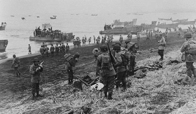 Landing boats pouring soldiers and their equipment onto a grassy beach at Massacre Bay in Attu Island, Alaska.