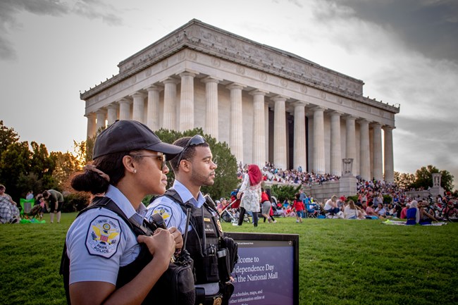 Two USPP officers in uniform stand in front of the Lincoln Memorial at an event.