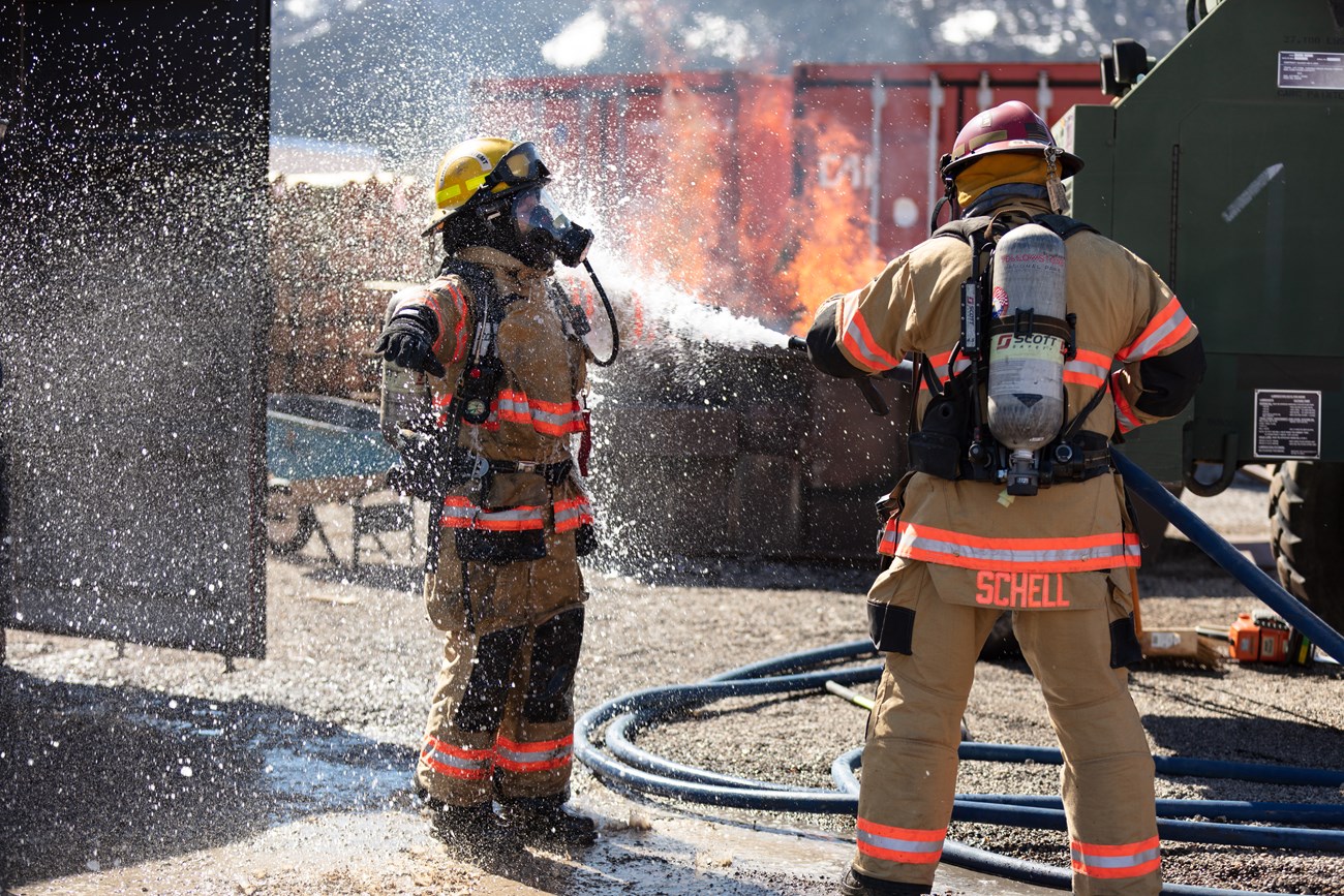 NPS Structural Fire Operations Chief Michael Schell conducts a field-level cancer prevention decontamination on a firefighter during refresher training at Yellowstone National Park in May 2019.
