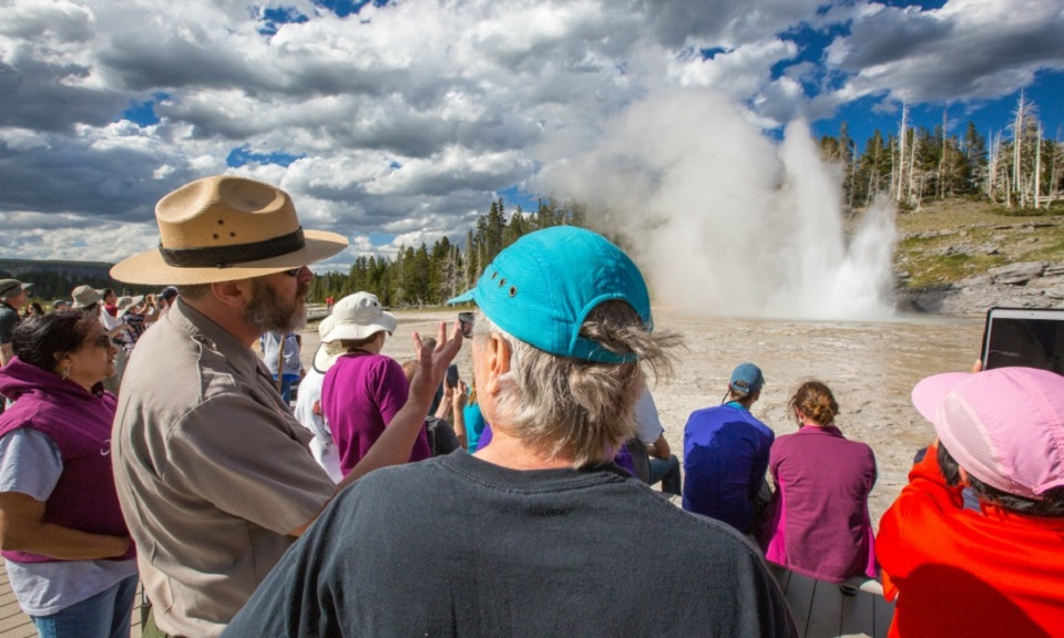 Ranger talking to a visitor in front of a geyser