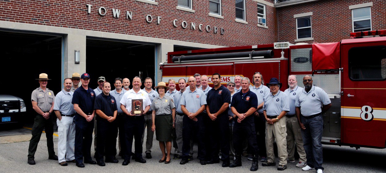 Group photo of Concord Fire Department with a plaque from NPS