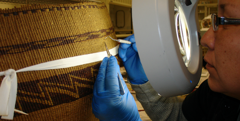 A woman in blue gloves cleans a large basket.