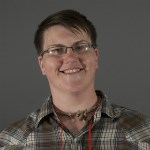 lt= Headshot of woman in glasses and plaid.