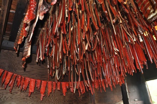 Salmon hanging from the rafters of a smoke house.