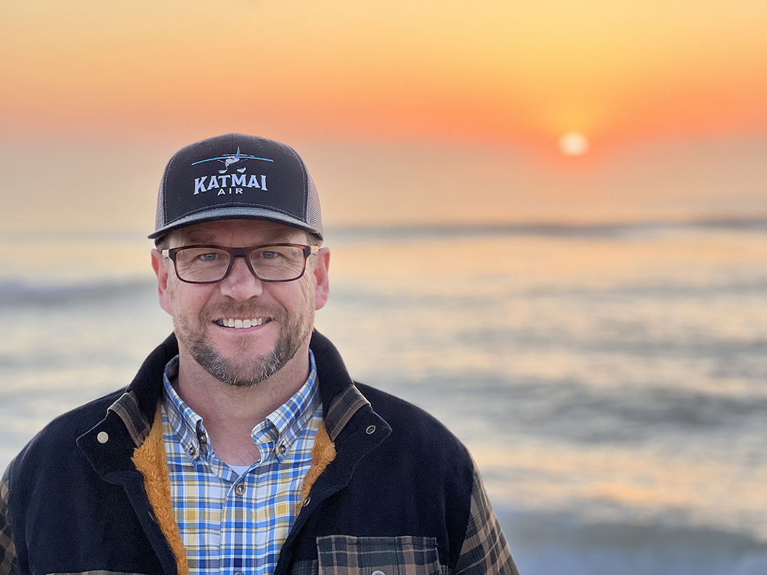 Chuck Russell Man poses in front of a sunset.