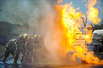 Firefighters use water to quench flames coming from metal structure.