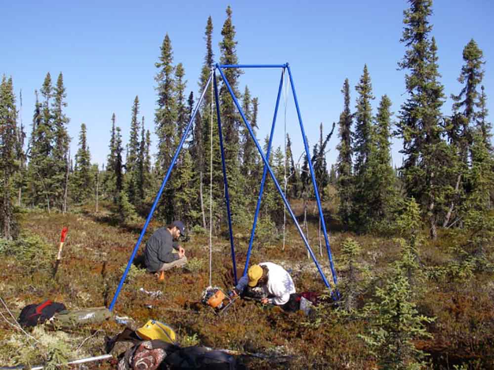 Researchers in the field measuring tundra.