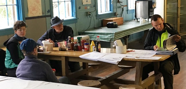 Professionals meet around a cafeteria table at the historic NN Cannery mess hall