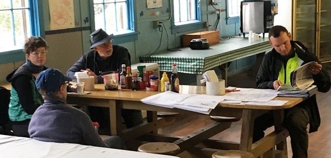Professionals meet around a cafeteria table at the historic NN Cannery mess hall Professionals meet around a cafeteria table at the historic NN Cannery mess hall