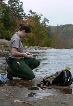 Ranger taking measurements near river.