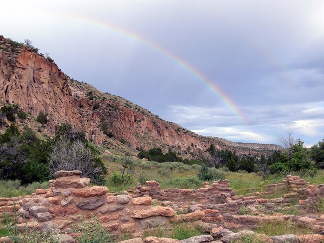 lt= A double rainbow against the sky with the walls of Tyuonyi in the foreground.