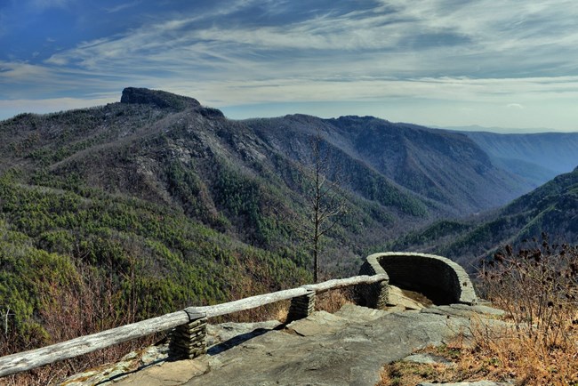 An overlook into a valley with tree-covered hillsides.