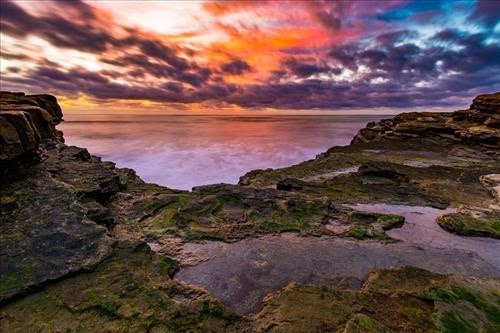 Colorful sunset reflected in the ocean and tide pools.
