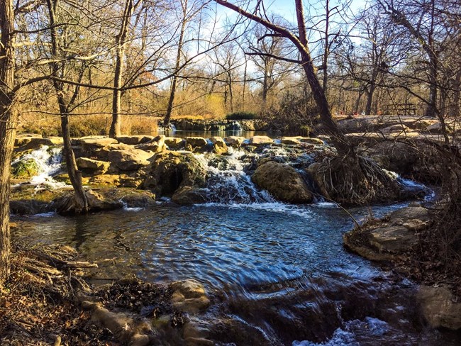 Visitors in picnic area near a rocky dam.