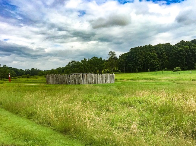 A wooden fort in the middle of a green field.