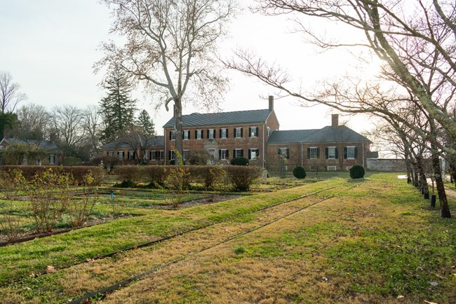 View of Chatham Manor from gardens in the front of the long brick house.