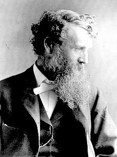 NRCA JOMU Black and white photo of John Muir in profile, wearing a suit, and sporting his trademark beard.
