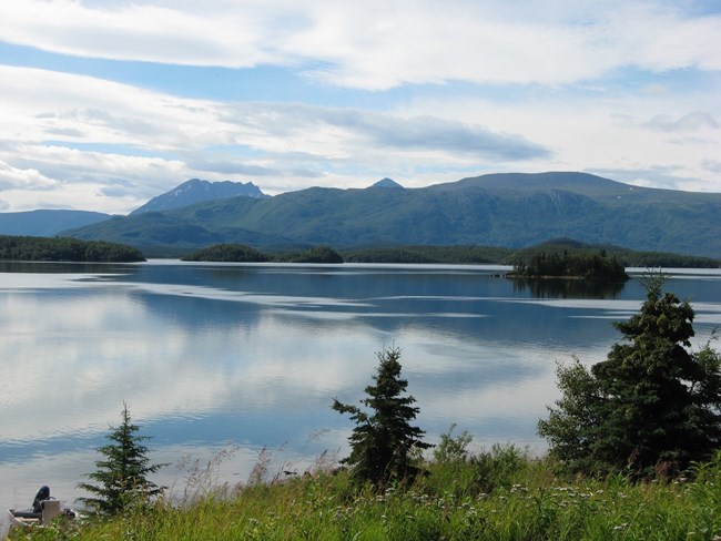 A still lake with islands and a mountain range in the background.