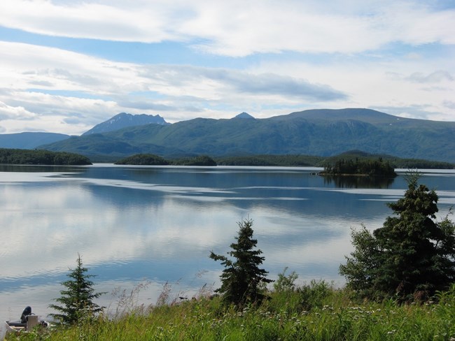 . A still lake with islands and a mountain range in the background.