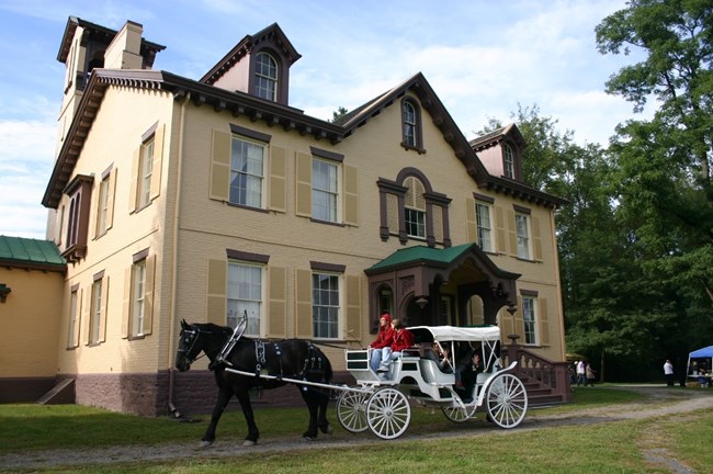 A horse-drawn carriage in front of a manor house.